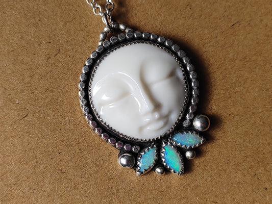 A handcrafted silver pendant with white porcelain moon face and 3 marquise shaped opals.