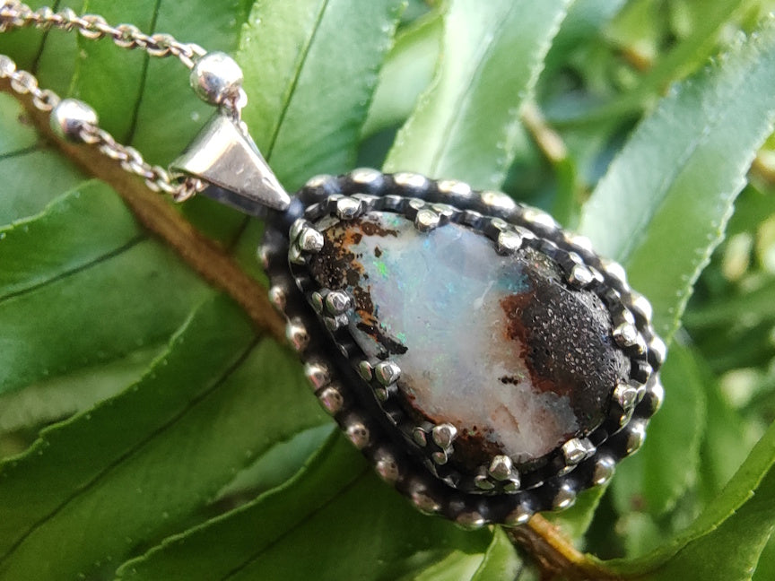 Handmade silver necklace with a pendant featuring a Yowah Boulder  opal stone on green fern leaves.