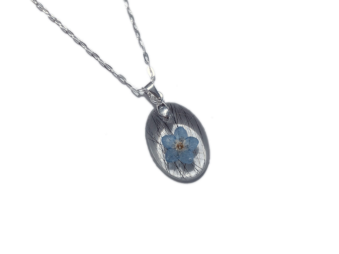 A small oval shaped memorial necklace with loved ones hair