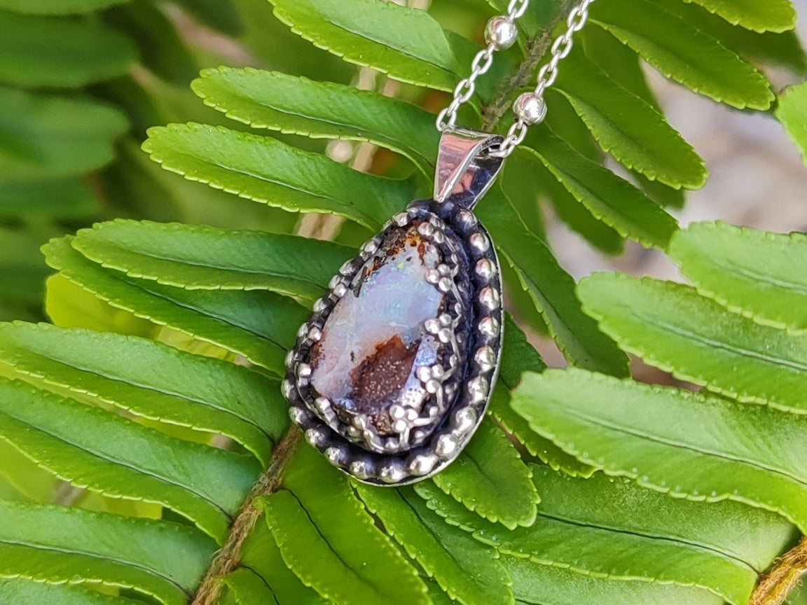Handmade silver necklace with a pendant featuring a Yowah Boulder  opal stone on green fern leaves.