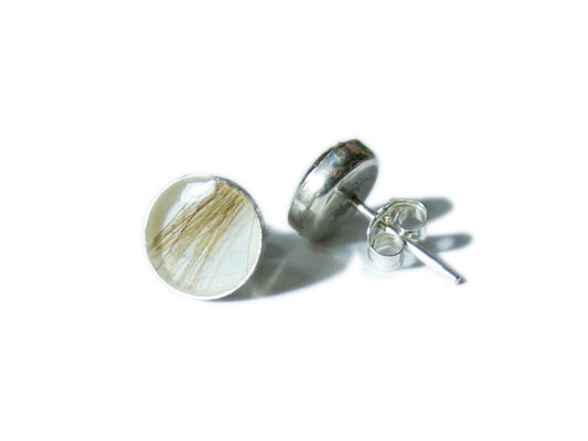 A pair of sterling silver stud earrings, preserving a small amount of hair