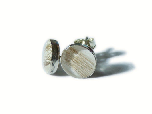 A pair of handmade stud earrings in sterling silver, with small amounts of hair preserved as the "gem"