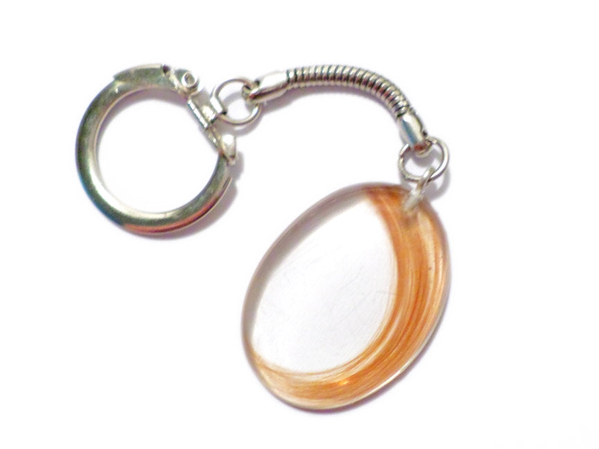 A large oval shaped memorial keychain with loved ones hair